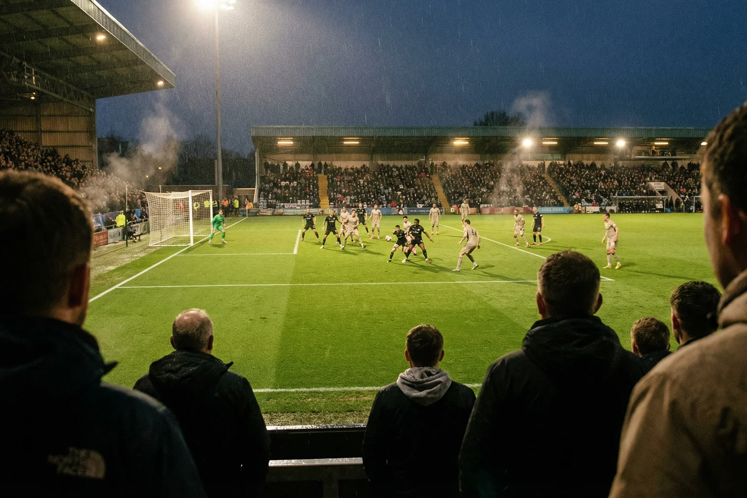 Tifosi in uno stadio di calcio durante una partita in diretta con il campo verde illuminato